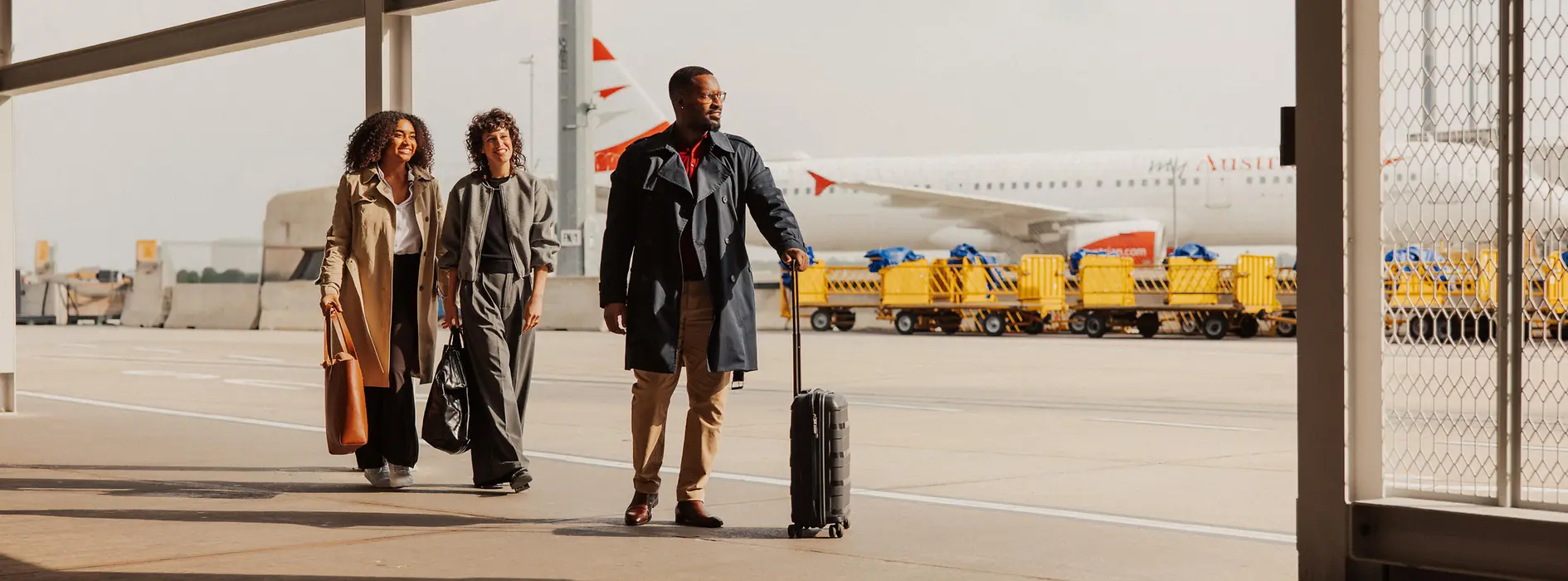 People with carry-on luggage in the outdoor area of Vienna International Airport on their way to the terminal.