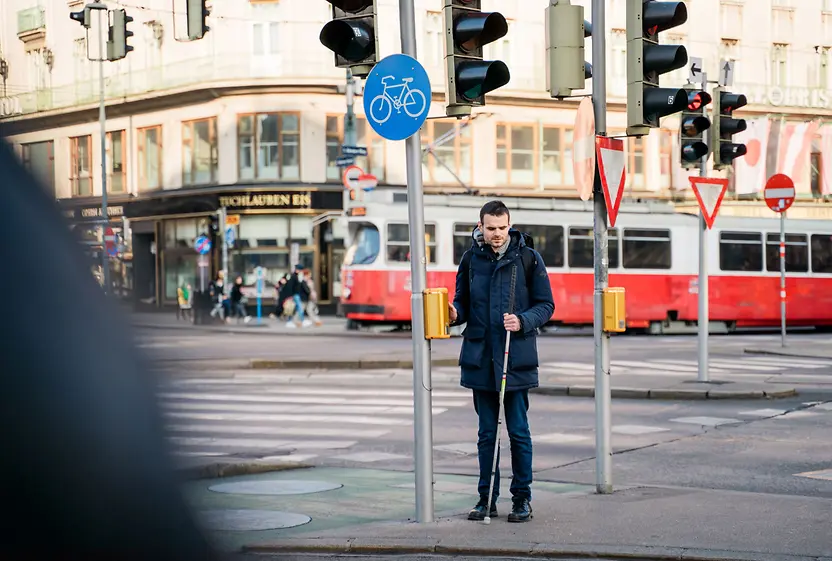 Blinde Person nutzt Akustik-Taktile-Ampel.