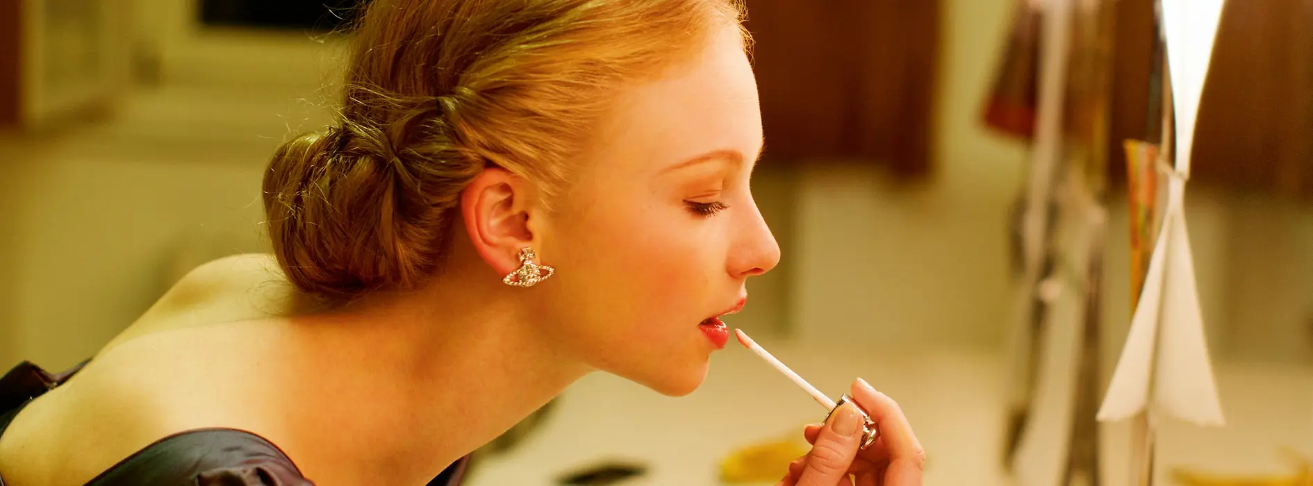 Woman putting on makeup in front of a mirror in the Opera Ball cloakroom