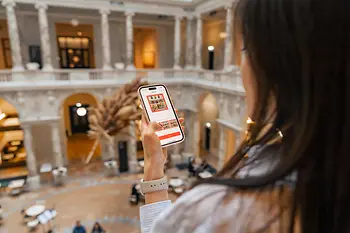 Dark-haired lady looking at the display of her smartphone.